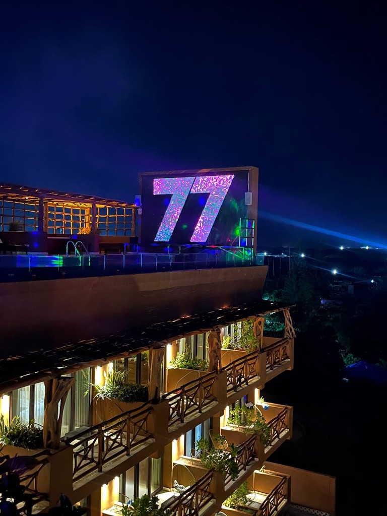 The illuminated 77 screen above the rooftop pool at night